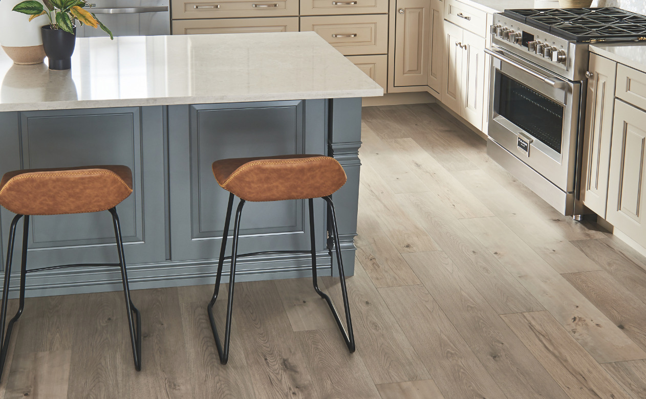 Light brown laminate flooring in a kitchen with an island and two barstools